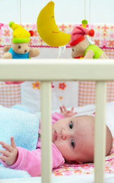 baby lying in a white crib with crib mobile